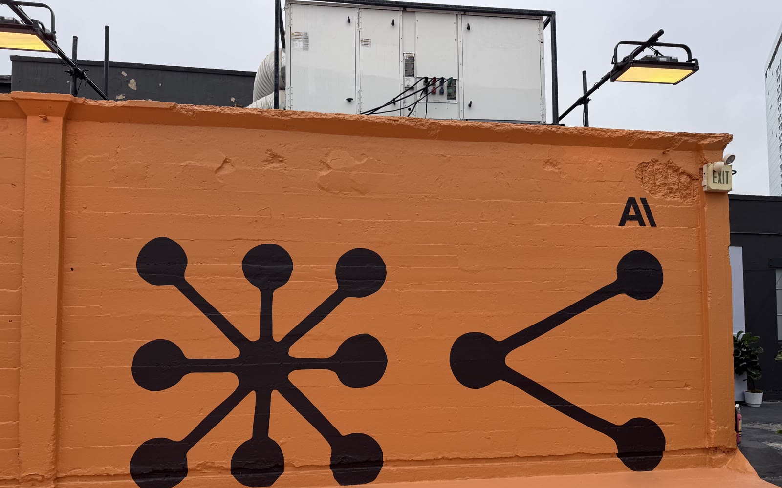 Mural at Code w/ Claude Extended — the Claude molecular logo painted on an orange wall